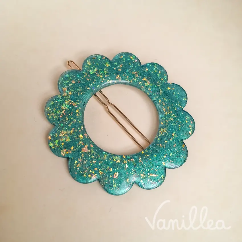 Gros plan sur barrette fleur turquoise pailletée et détails dorés