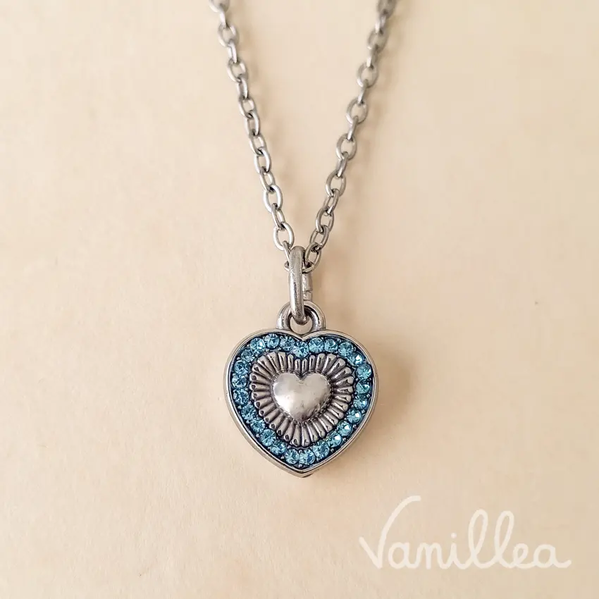 Collier cœur argenté à strass bleus porté autour du cou