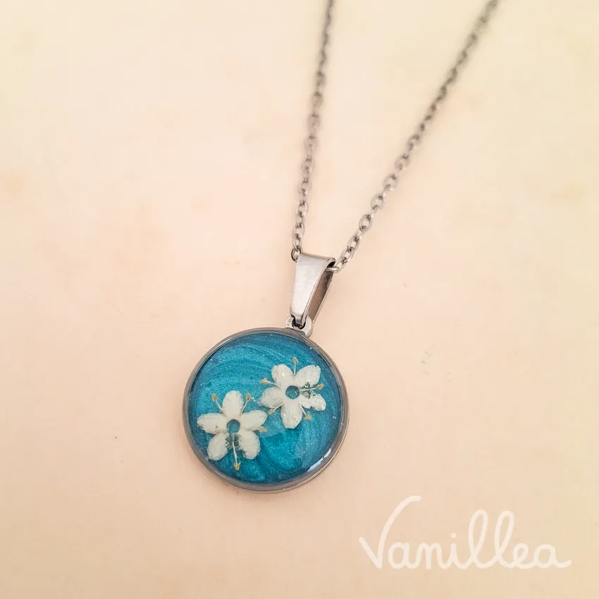 détail du pendentif myosotis résine bleue argenté avec fleurs blanches