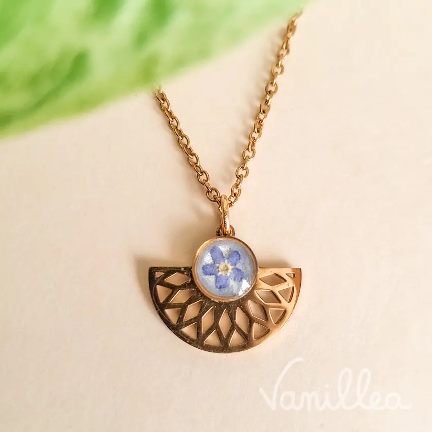 Détail du pendentif éventail doré avec myosotis bleu sur collier