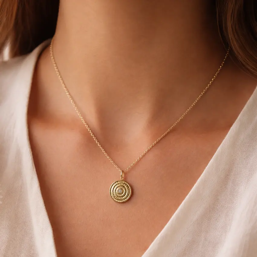 Collier médaille spirale dorée porté avec chaîne fine en acier inoxydable