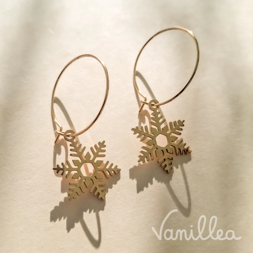 Boucles d'oreilles créoles dorées avec flocons de neige suspendus, vue de face