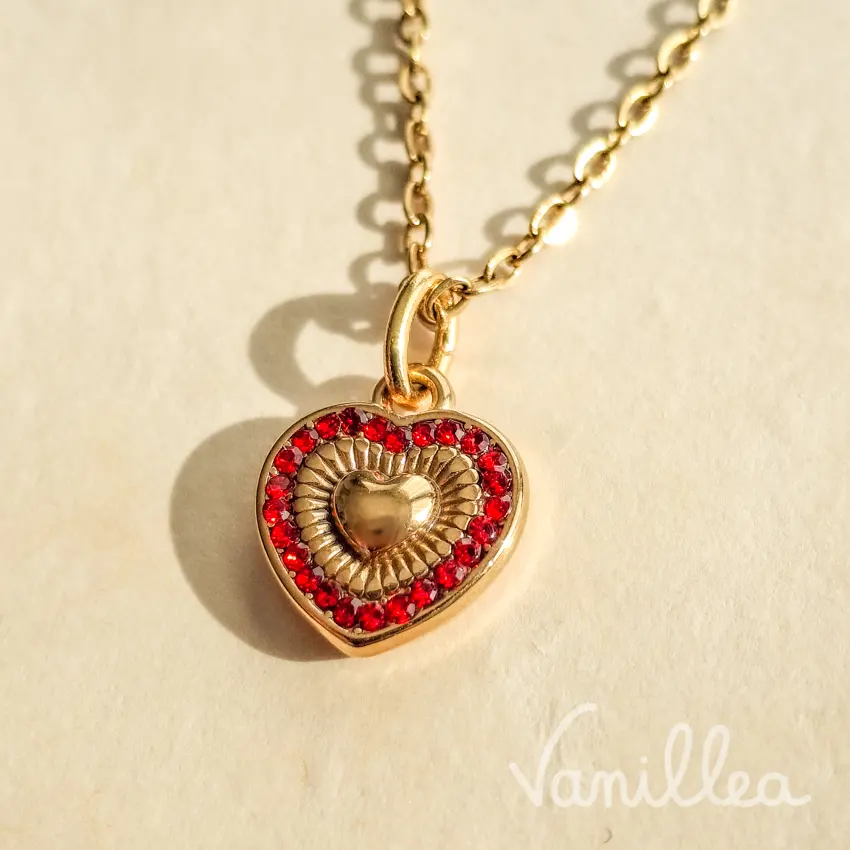 Détail du collier cœur strass rouge avec motif rayonnant doré